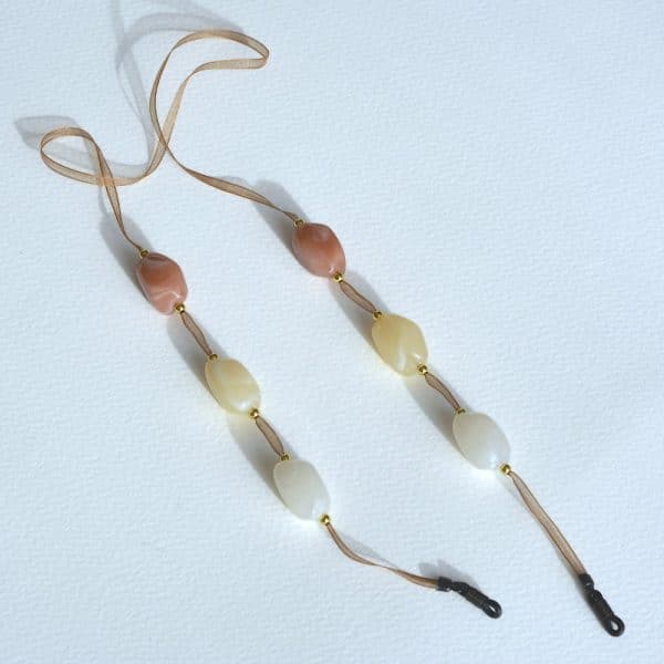 Cordon de lunettes Mousseline Perles baroques et perles métal doré. Cordon ruban en mousseline très résistant, finition noire. coloris : cordon mousseline marron / perles baroques caramel au lait, crème, blanc / perles métal doré Système de fixation Classique : Ses boucles en caoutchouc ultra résistantes garantissent une fixation sûre et en font un produit durable. Taille disponible 65 cm. Modèle : Gourmandise